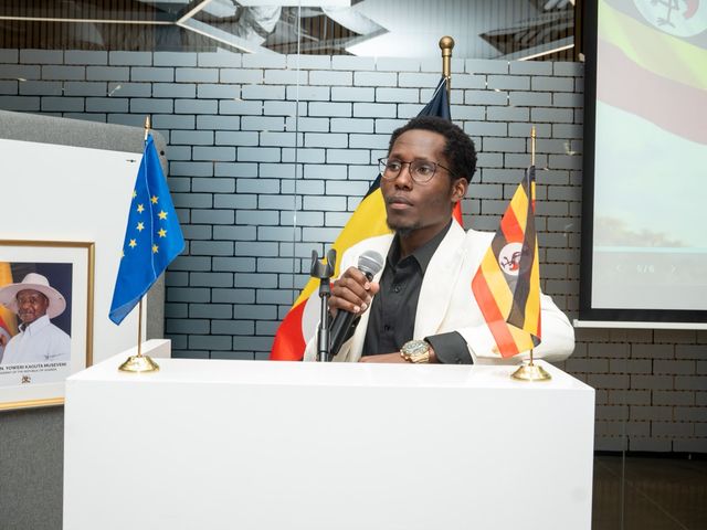 Speaker at the podium between the flags of the European Union and Uganda